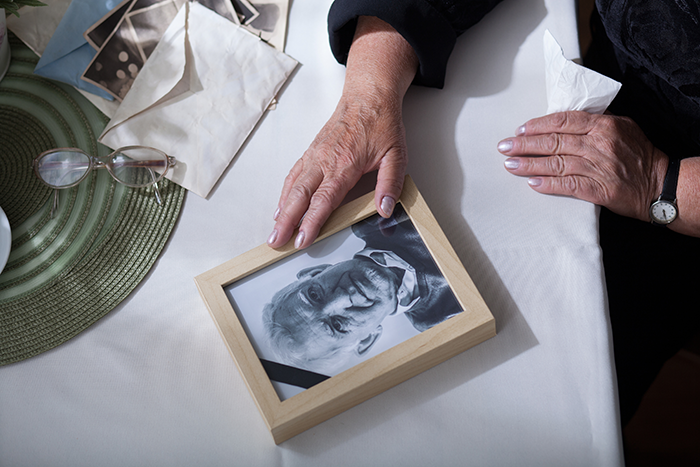 Photo of a person's hands touching a picture frame with a picture of an older man