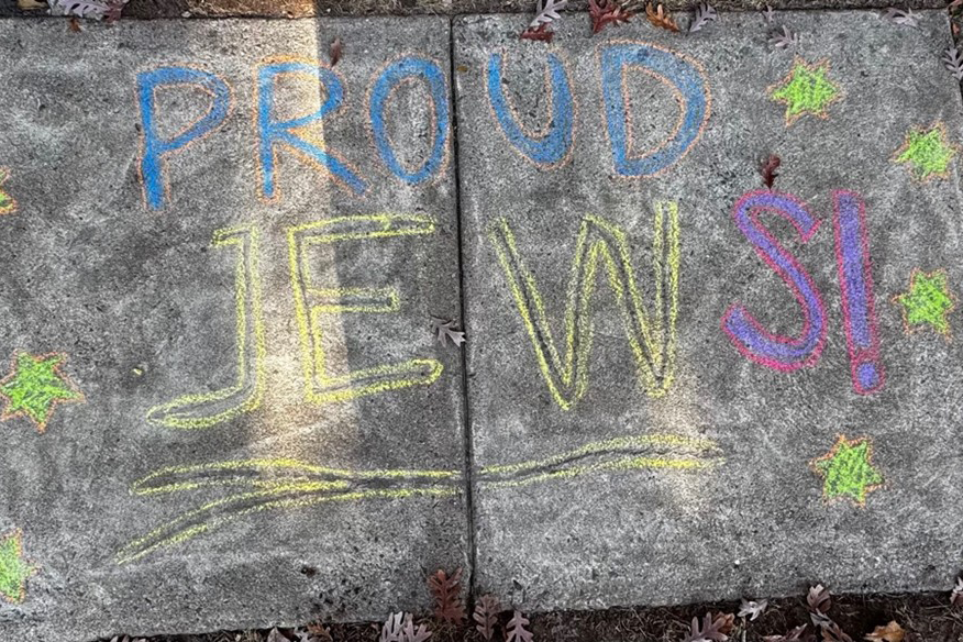 Photo of the words "Proud Jews" written in chalk on the sidewalk