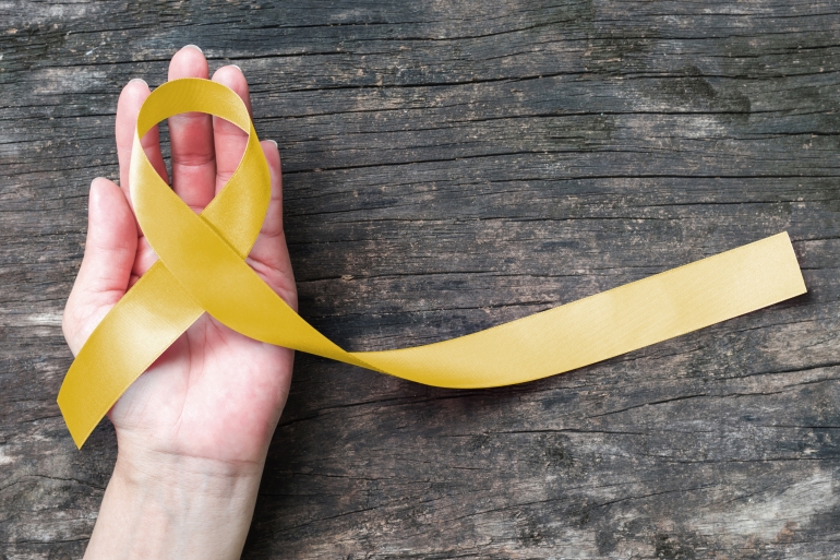 A hand holding a yellow ribbon